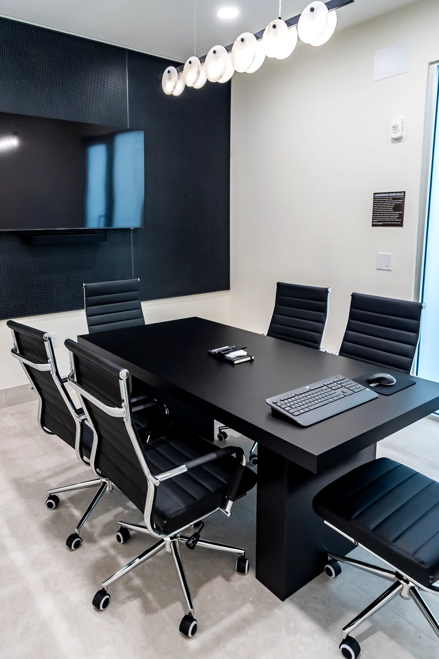 Conference room at Five85West with a black table, chairs, and wall screen