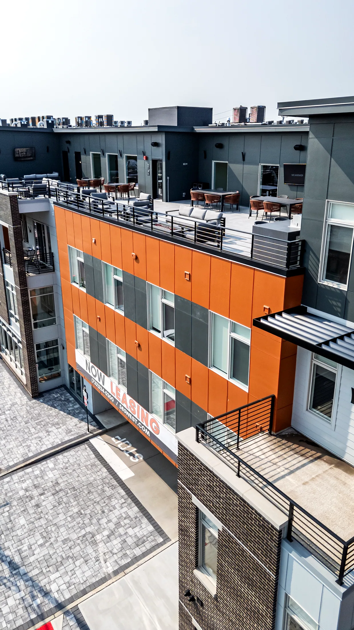 Esquina de Five85West con revestimiento naranja y el barandal de la terraza en la azotea arriba