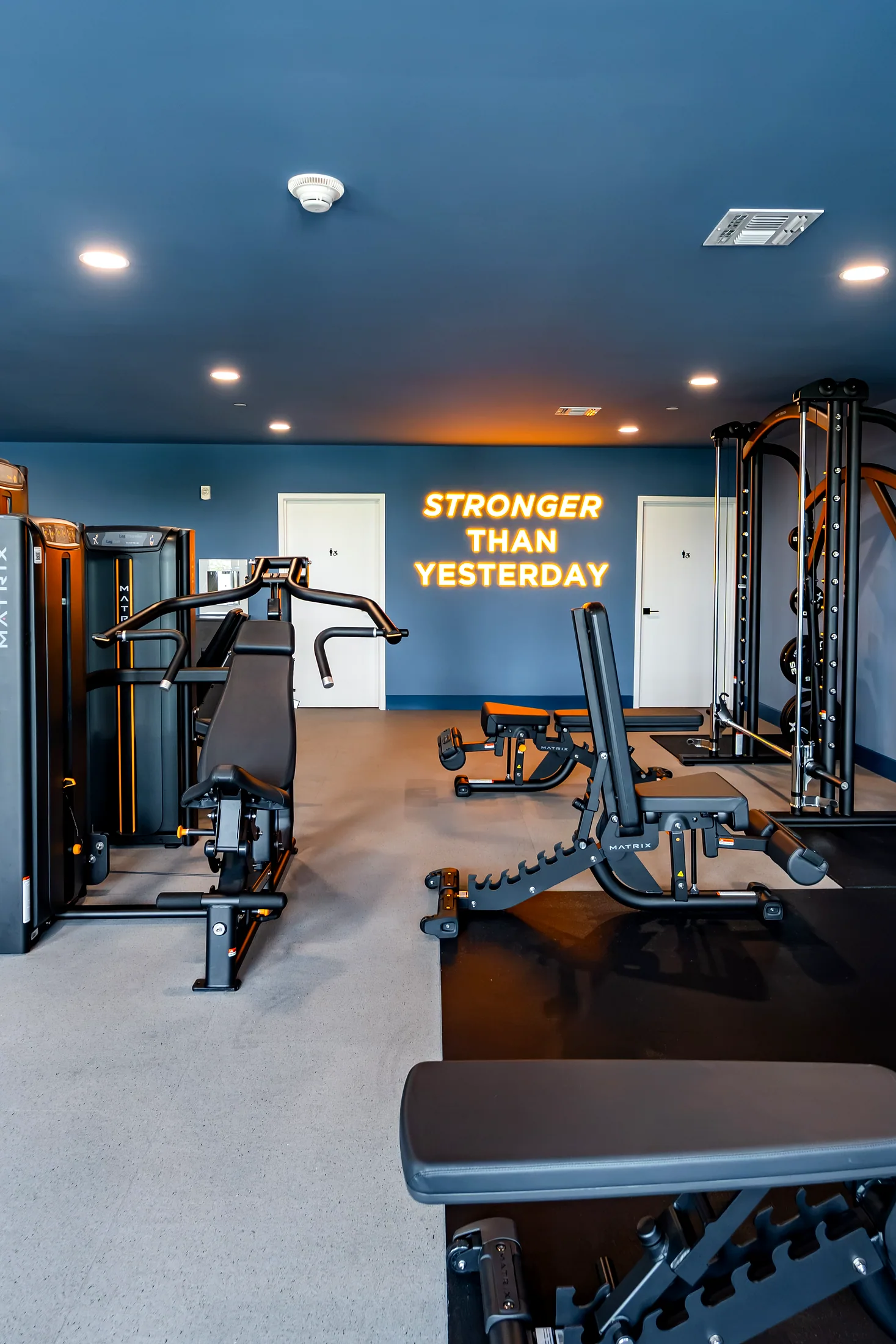 Fitness center at Five85West with the Stronger Than Yesterday neon sign