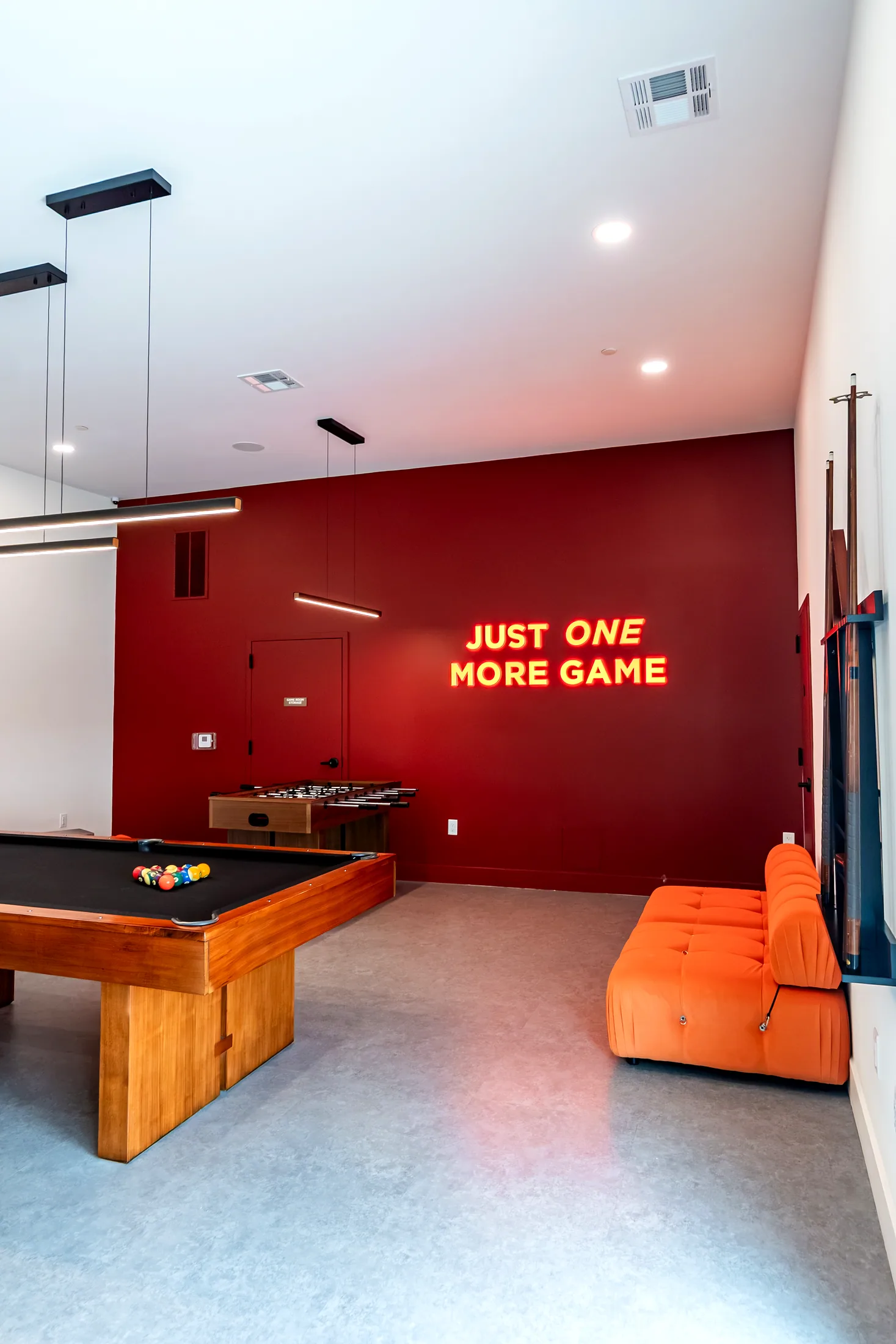 Game room at Five85West with a pool table, red wall, and the Just One More Game neon