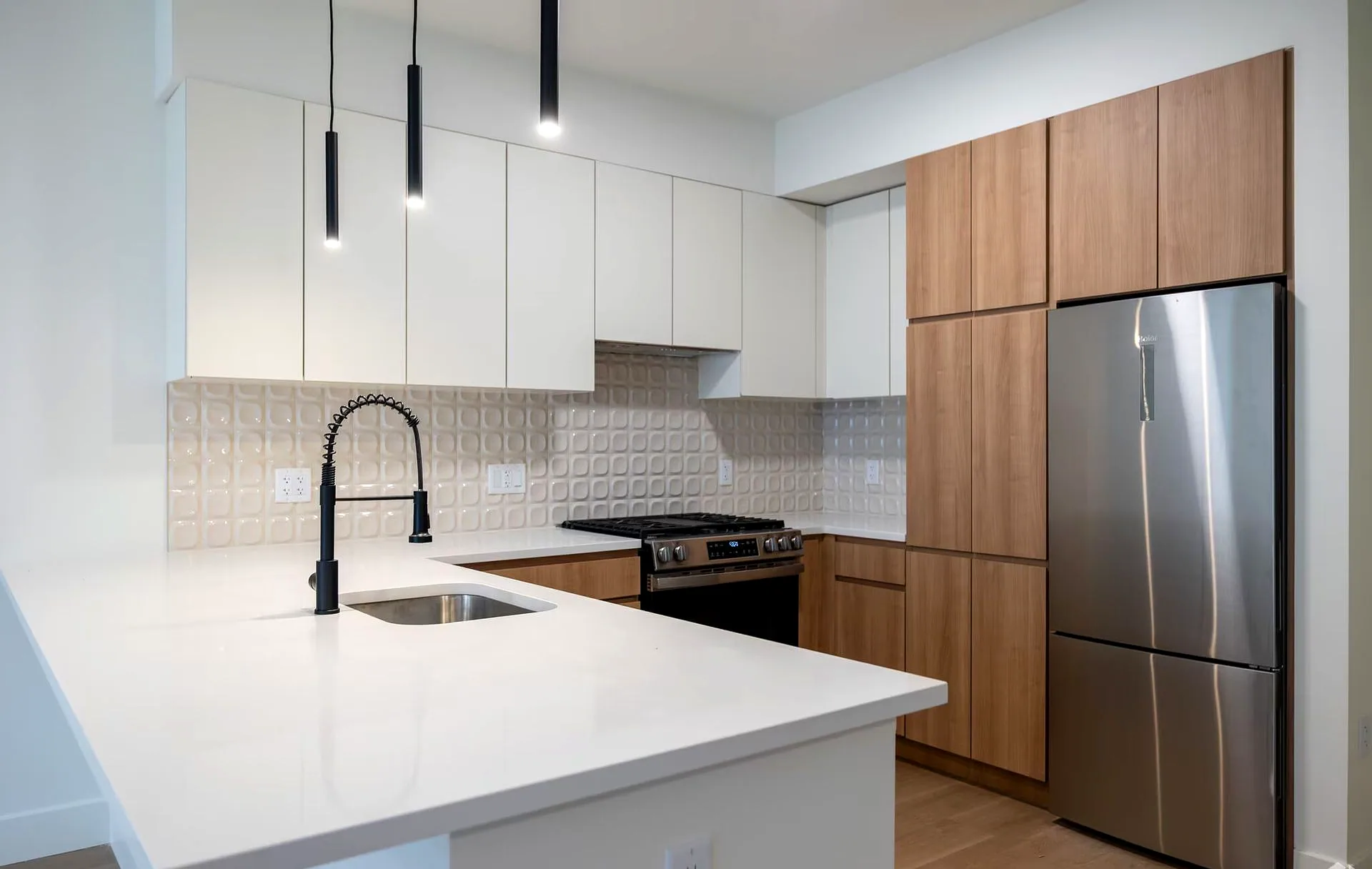 Cocina con cubiertas de cuarzo blanco, gabinetes de madera cálida y herrajes en negro mate